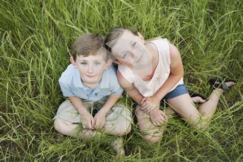 Brother And Babe Sitting Side By Side In Long Grass Photofolio Stock Photos