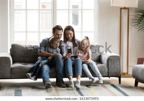 Happy Young Parents Sit On Couch Photo De Stock Modifiable 1613073493
