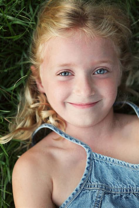 content little blonde girl laying in grass smiling by dina marie giangregorio