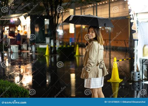 A Woman Is Walking Alone At The Night Street In The Rainy Season Stock