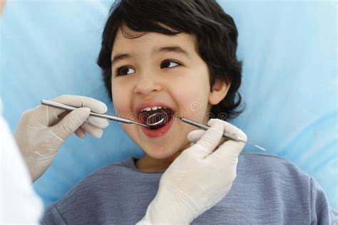 Cute Arab Boy Sitting At Dental Chair With Open Mouth During Oral