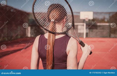 beautiful and slender girl with a racket plays tennis girl stands with her back to the viewer