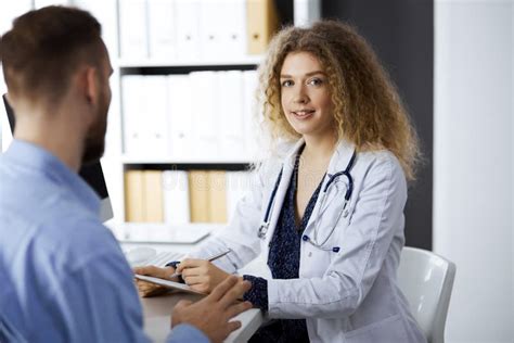 Female Doctor And Male Patient Discussing Current Health Examination While Sitting In Clinic