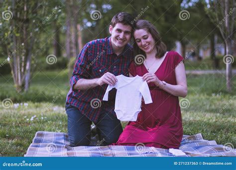Young Couple Soon To Be Parents Holding A Little Baby Cloth Together