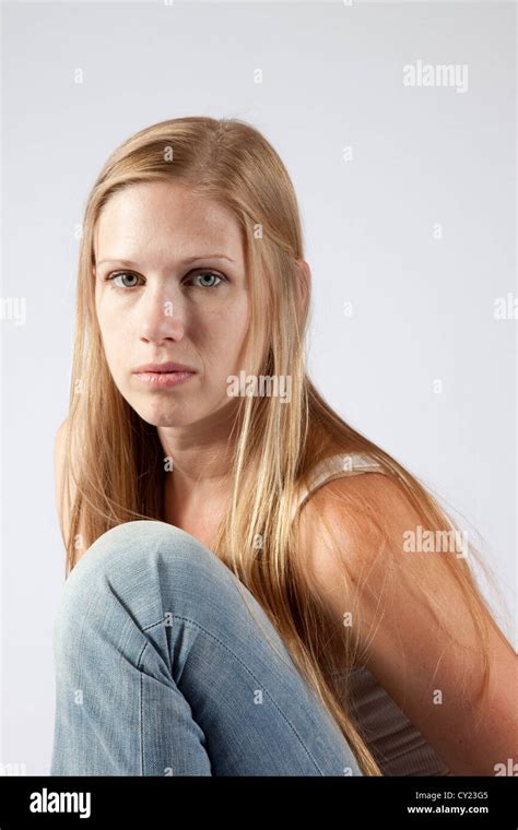 Pretty Blond Woman Sitting With Her Knee Up To Her Chest And Looking At