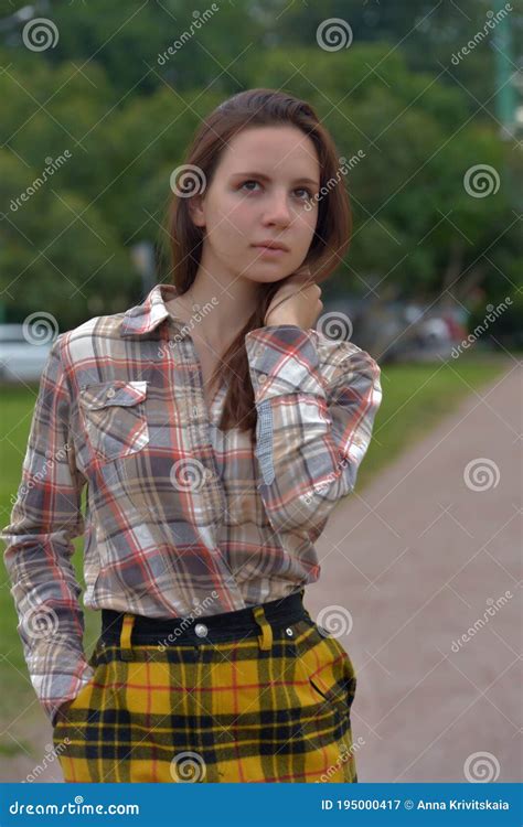 Slender Brunette Girl In A Plaid Skirt In The Summer In The Park Stock
