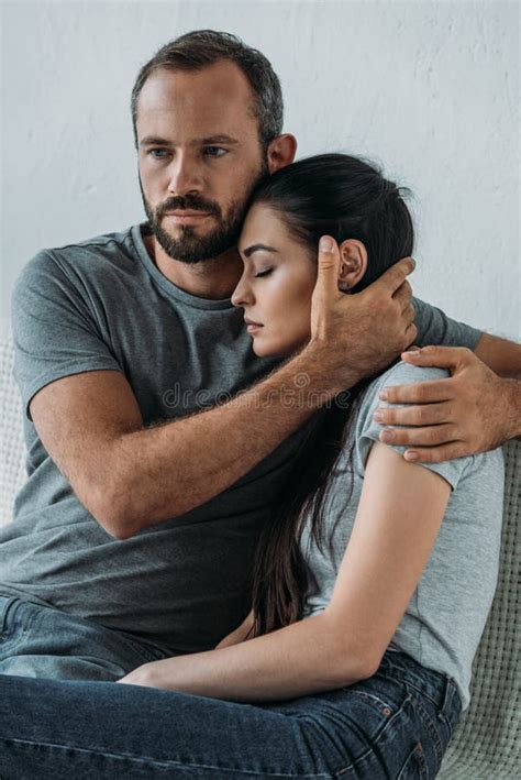 Bearded Man Supporting And Hugging Stressed Sad Woman Sitting Stock
