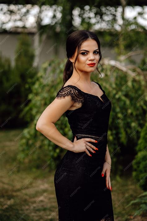 Premium Photo A Woman In A Black Dress Stands In Front Of A Green