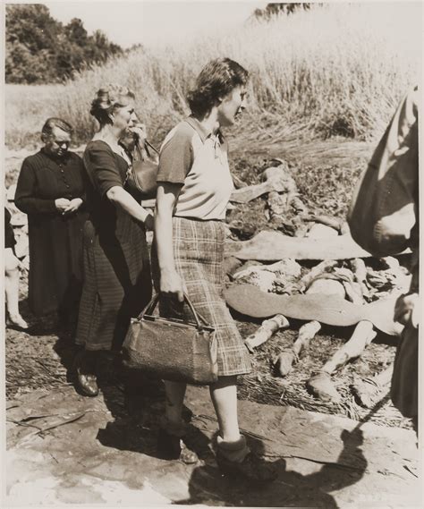 german women from nammering are forced to walk among the corpses of prisoners exhumed from a