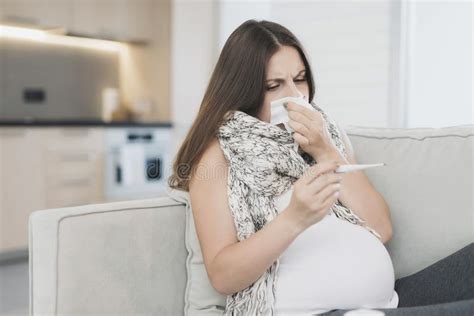 Sick Pregnant Woman Sitting At Home On The Couch She Flies Herself Into A Paper Napkin Stock