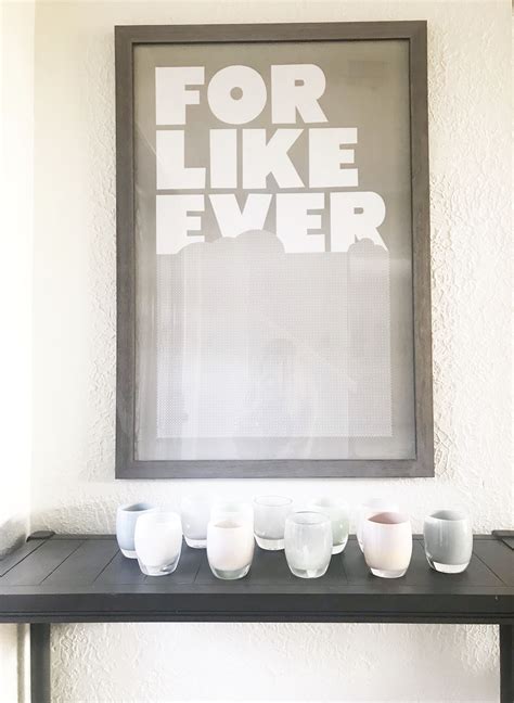 A Black Table With White Cups On It And A Framed Poster Above The Top