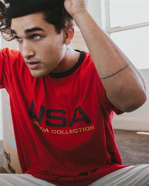 A Man Sitting On The Floor Wearing A Usa T Shirt And Holding His Hair