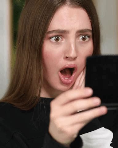 A Woman Is Holding Up Her Cell Phone To Take A Selfie With It S Mouth