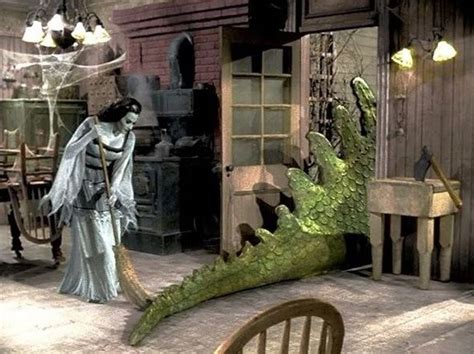 Lily Munster Sweeps The Kitchen As Spot The Dragon Leaves The Room On