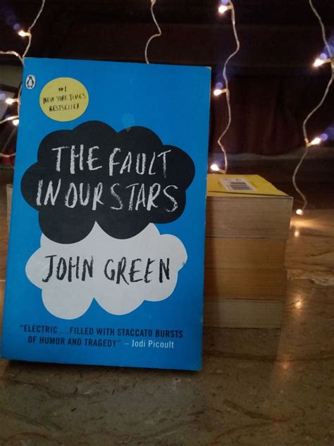 the fault in our stars by john green is sitting on a table next to some books