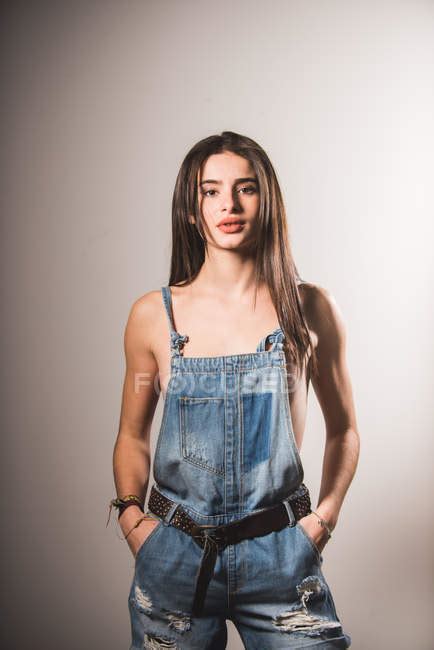Brunette Topless Girl Posing In Denim Overall And Looking At Camera