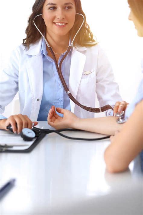 Doctor Checking Blood Pressure Of Female Patient While Sitting At The