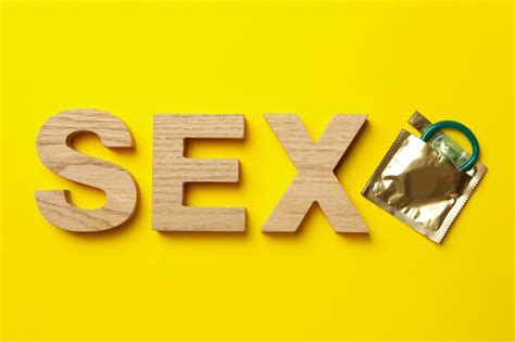premium photo word sex made of wooden letters and condom on yellow surface