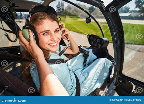 Smiling Female Pilot Putting On Headphones Before Flight Stock Image