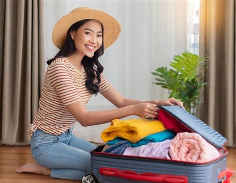 premium ai image beautiful asian woman pack things or clothes into a suitcase preparation for