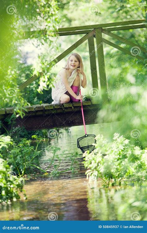 Young Girl Catching Fish With Net From Wooden Bridge Stock Image