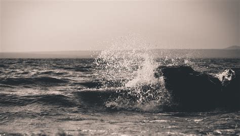 A Black And White Shot Of Water Splashing Over Dark Waves Water