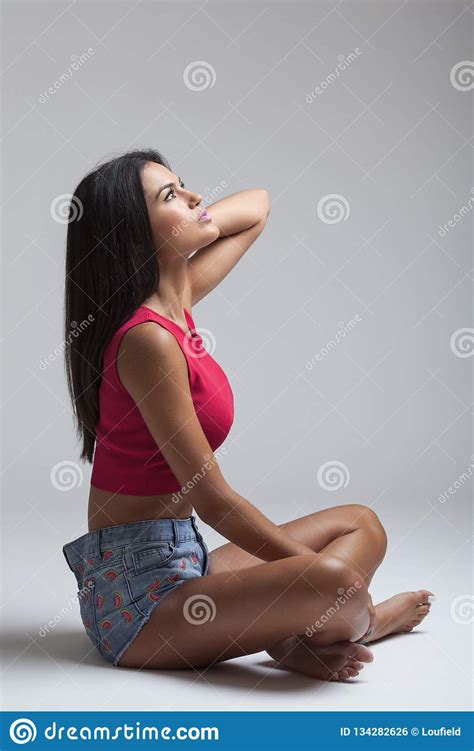 Kaukasische Vrouwenzitting In Korte Jeans En Rode T Shirt Stock Foto