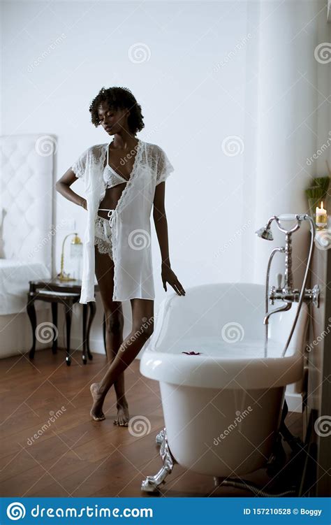 Pretty African American Woman Standing By The Bathtub In The Bathroom