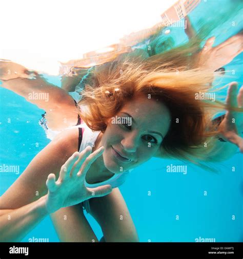 Attractive Female With Eyes Open Looking And Smiling While Underwater In Swimming Pool Stock