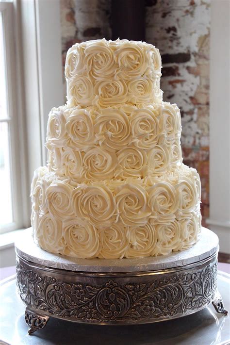 A Three Tiered Cake With White Frosting Roses