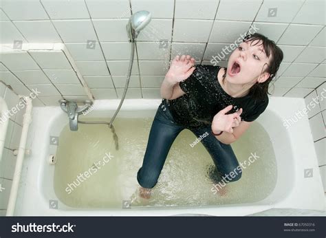 Girl In Clothes In The Bathroom Under The Shower Stock Photo