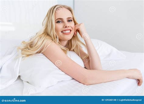Beautiful Young Blonde Woman Lying On Bed And Smiling Stock Photo
