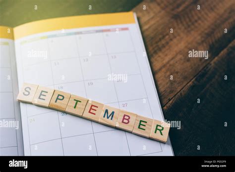 Closeup Of September Alphabet Tile On Planner Book Calendar On Wooden