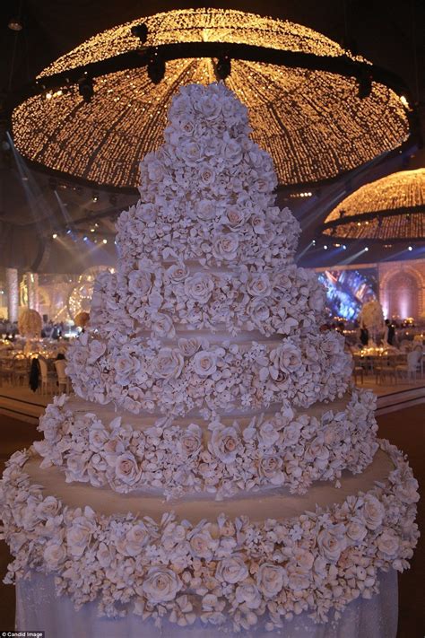 a white wedding cake with flowers on it and an umbrella in the background that says take an