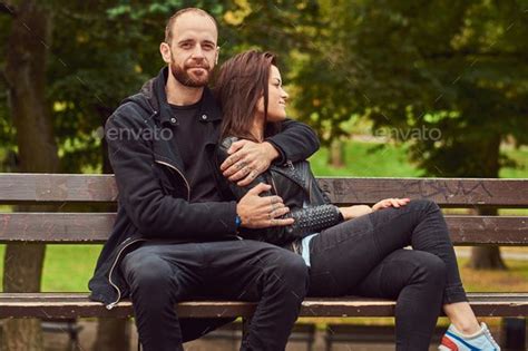 Attractive Modern Couple Sitting On A Bench In A Park Couple