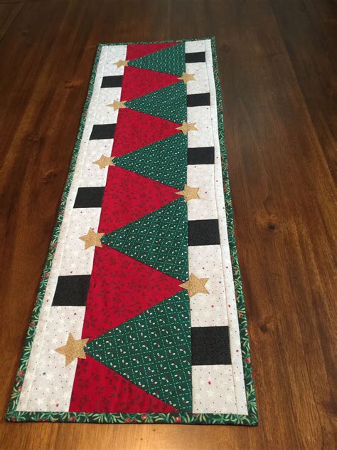 A Christmas Table Runner With Red Green And Gold Stars On It Sitting