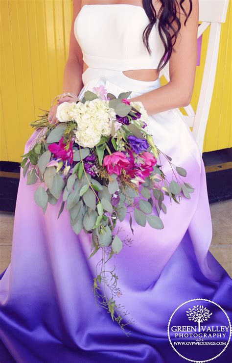 A Woman In A White And Purple Dress Holding A Flower Bouquet On Her