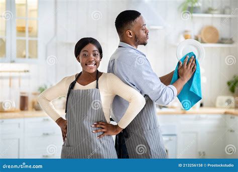 Portrait Of Positive Black Woman And Her Husband Wiping Dishes At