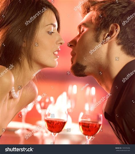 Young Happy Amorous Couple Kissing On Romantic Date At Restaurant