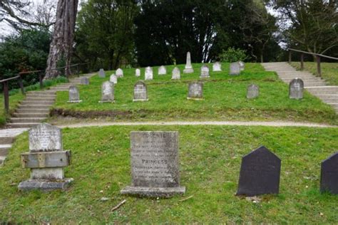 An Old Cemetery With Many Headstones On The Grass And Steps Leading Up