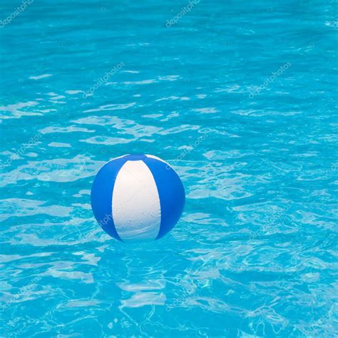 White And Blue Beach Ball Floating On A Sparkling Blue Swimming Pool