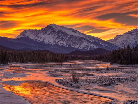 Sunset in winter mountains with pine trees frozen river snow red sky ...