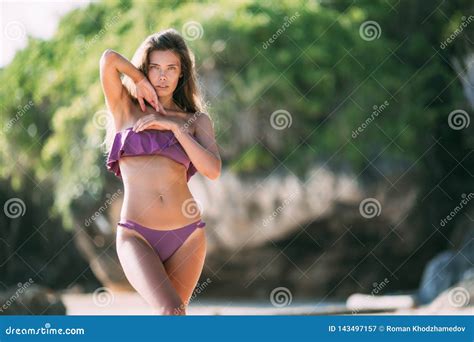 menina sexy no roupa de banho roxo da cor que levanta no dia ensolarado no sandy beach imagem