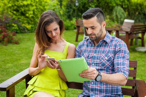 Couple Sitting On The Bench In The Garden And Using Smartphone A Stock Image Image Of Mobile