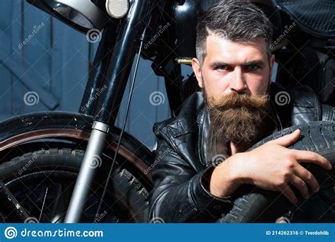 Handsome Bearded Biker In Leather Jacket Sitting Near Motorcycle In