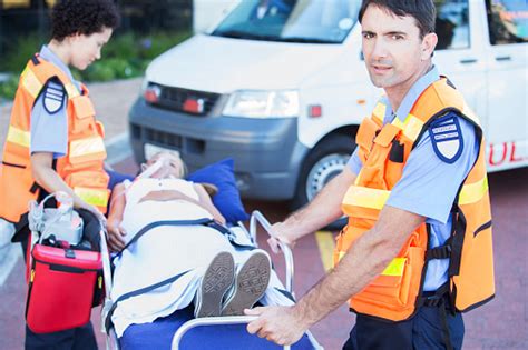 photo libre de droit de des ambulanciers paramédicaux conduisent un patient sur une civière dans