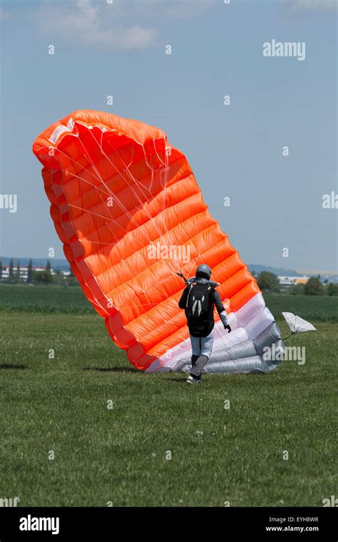 Skydiver With Orange Parachute Runs After Landing In A Field Stock