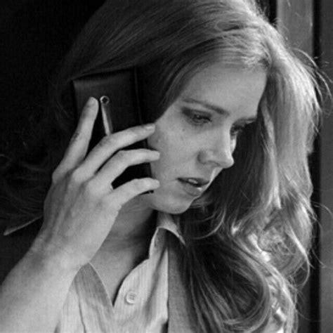 black and white photograph of a woman talking on a cell phone while holding her hand up to her ear