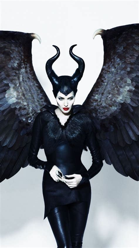 A Woman Dressed In Black With Large Wings On Her Head And Hands Behind Her Back