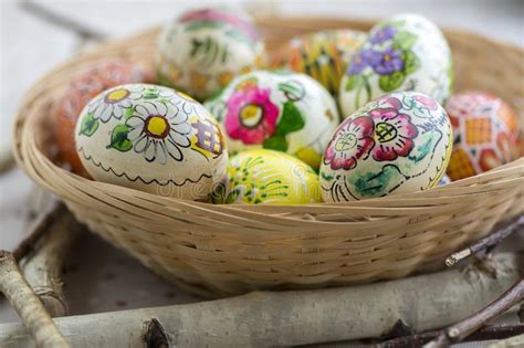 Colorful Painted Easter Eggs In Brown Wicker Basket On Branches
